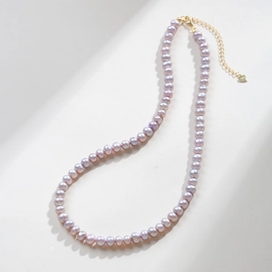 Detail of lavender freshwater pearls with a gold lobster clasp and heart charm