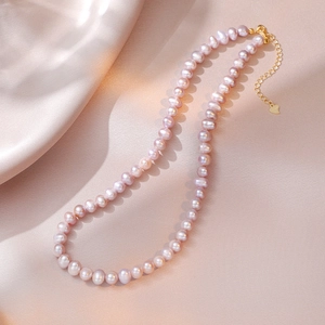 Detail of S925 silver lobster clasp and pink freshwater pearls on a silk background