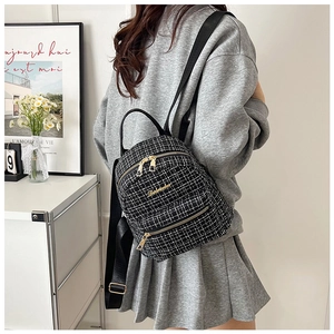 Vue latérale d'un mini sac à dos en tweed bicolore porté par un mannequin dans un intérieur