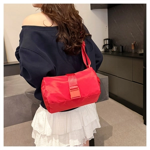 Close-up of a red nylon crossbody toast bag with adjustable strap on a female model