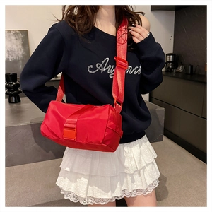 Close-up of red nylon pillow bag with adjustable wide strap and plastic buckle detail
