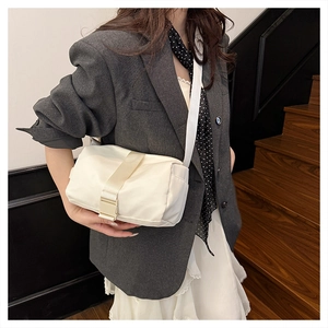 Detail view of cream Oxford fabric crossbody bag showing wide strap and buckle closure