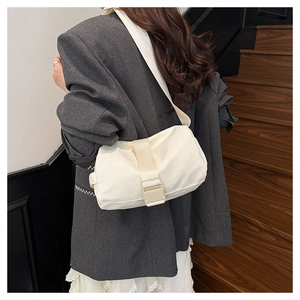 Chic white nylon pillow bag with wide woven strap shown in a lifestyle indoor setting