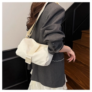 Detail view of cream oxford fabric crossbody bag with wide shoulder strap and plastic buckle