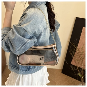 Detail of transparent PVC crossbody bag showing capacity with cosmetics and gold chain