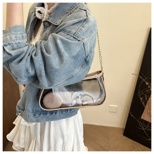 Close-up of clear PVC shoulder bag with gold chain strap showing interior storage space