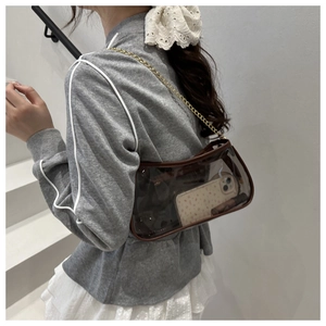 Detail of transparent PVC shoulder bag with brown leather trim and golden chain strap