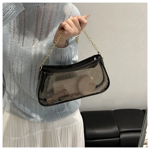 Detail shot of black semi-transparent PVC shoulder bag with elegant gold chain strap