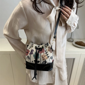 Boho chic drawstring bucket bag with vintage floral embroidery and black leather trim