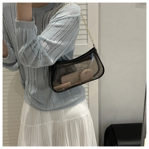 Detail of transparent PVC shoulder bag with golden chain strap and makeup items
