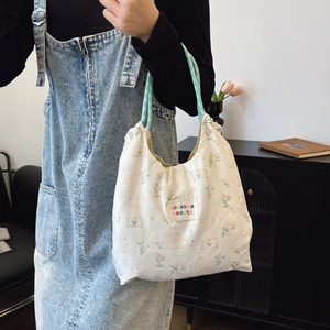 Floral canvas tote bag with rabbit prints and green rope handles worn by a model
