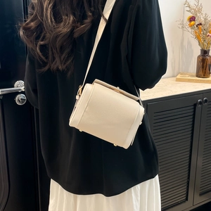 Cream box crossbody bag in lychee pattern leather with gold buckle shown on a model