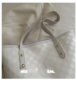 Detail of white quilted tote bag with checkered texture and gold rivet hardware