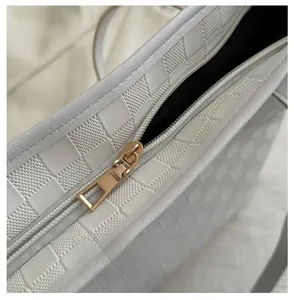Detail of smooth gold zipper and woven checkerboard pattern on a white tote bag