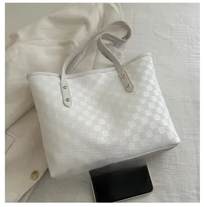 Detail of white tote bag featuring woven checkerboard texture and slim rivet straps