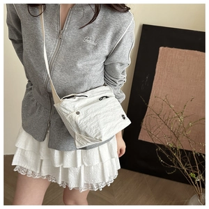 Detail of white crinkled nylon crossbody bag with zipper and decorative pull cord