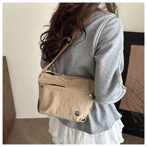 Adjustable nylon shoulder strap and metallic brand logo on khaki crossbody bag detail
