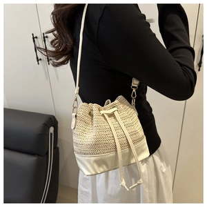 Detail of a beige woven straw bucket bag with drawstring closure and gold hardware