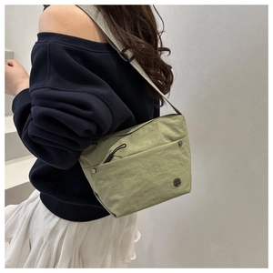 Primer plano de un bolso bandolera de nailon verde claro con correa ajustable