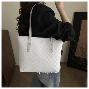 Detail showing white woven quilted tote bag texture with elegant gold stud accents