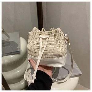 Detail of white woven straw bucket bag with drawstring closure and leather base