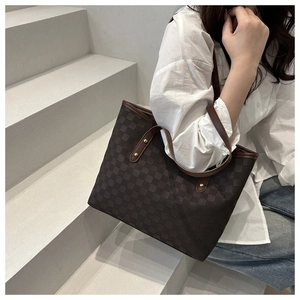 Macro detail of the checkered tote bag featuring brown leather handles and gold rivets