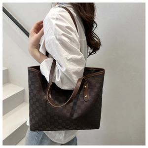 Detailed close-up of large brown checkered tote bag with leather handles and gold studs