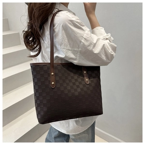 Close-up of deep brown checkered tote bag with reinforced handles on a fashion model