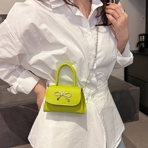 Minimalist lime green mini crossbody bag with a silver bow and metal chain strap