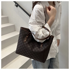 Detail of checkered tote bag showing leather straps and metallic rivets on dark brown fabric
