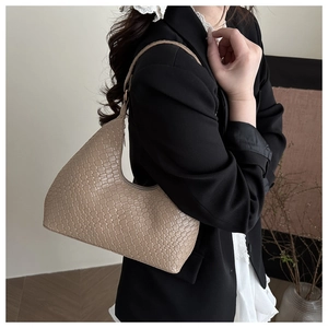Detail of beige woven texture and crescent shape on a vintage style faux leather handbag