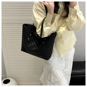Close-up of a black checkered tote bag with woven texture and metallic stud details