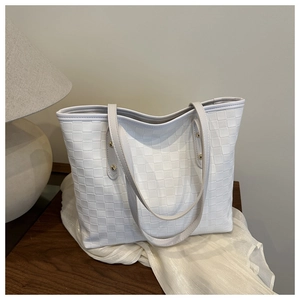 Detail shot of the white checkered texture and gold rivet hardware on the tote bag