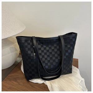 Close-up of black checkerboard quilted tote bag showing leather straps and metal rivets
