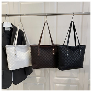 Detailed view of checkered leather tote bags with gold metal rivets in white, brown, and black