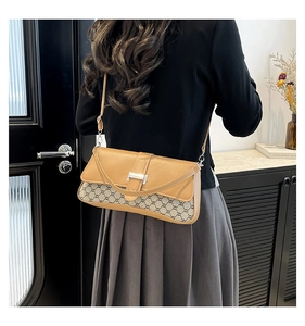 Brown vintage shoulder bag with monogram canvas and metal buckle detail worn by a model