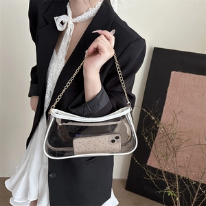 Clear PVC shoulder bag with white trim and gold chain strap shown on a female model