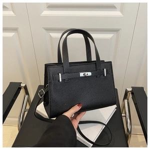 Detail of black lychee grain texture and silver metal lock on a classic tote bag