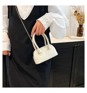 Close-up of white mini shell bag with lychee grain texture and golden chain strap