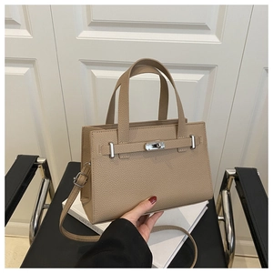 Detail shot of beige lychee texture leather handbag with silver metallic turn-lock buckle