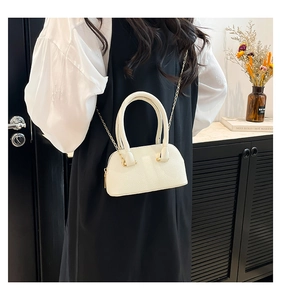 Close-up of white pebble leather mini shell bag with gold chain strap in lifestyle setting