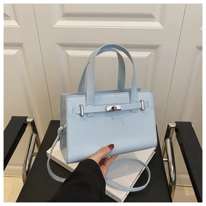 Detailed view of light blue lychee pattern leather bag with silver rotary lock and strap