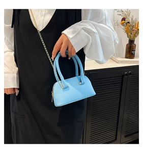 Detail of light blue shell bag with litchi texture and elegant golden chain strap