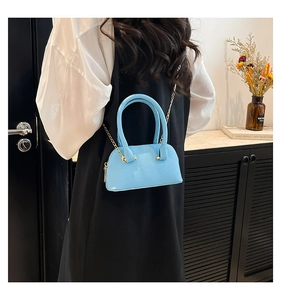 Close-up of light blue lychee pattern shell bag with golden chain strap on a model