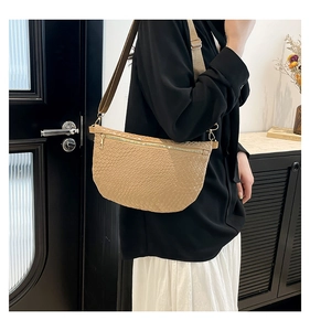 Detail of woven texture and gold zipper on tan crescent crossbody bag for women