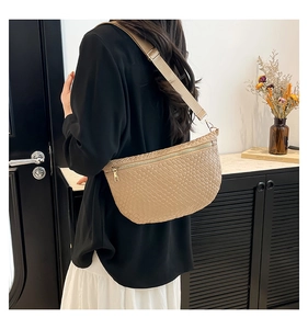 Detail of beige woven texture crossbody bag with adjustable strap and metal zipper