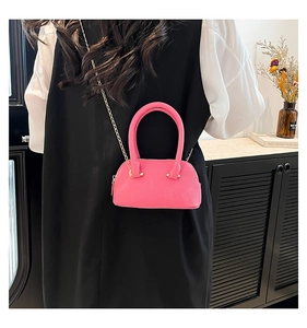 Detail of rose pink mini shell bag with lychee texture and gold chain strap in soft light