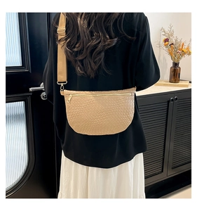 Detail of woven texture and adjustable canvas strap on the beige half-moon chest bag