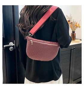 Detail of dark red crossbody bag with woven texture on model in minimalist setting