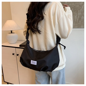 Detail of minimalist black nylon crescent bag featuring a stylish white fashion label